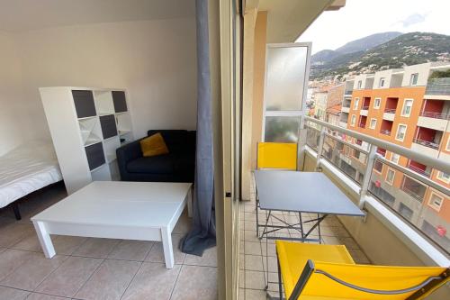 Ce petit appartement comprend une table blanche et des chaises jaunes. dans l'établissement 06BQ Studio close to the beach, à Roquebrune-Cap-Martin