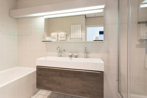 a bathroom with a sink and a tub and a mirror at Restaurant-Hotel de Watergeus in Noorden