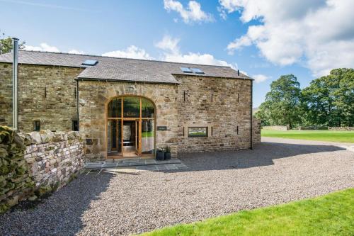 a stone building with a large glass door at Williamston Barn & Cowshed in Slaggyford