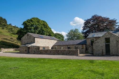 an old stone building with a grass field in front at Williamston Barn & Cowshed in Slaggyford