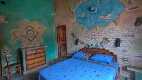 a bedroom with a blue bed and a painting on the wall at Casa Gaudi - House & Rooms in Teulada