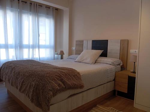 una camera da letto con un grande letto con una coperta marrone di Apartamento en Santander cercano al centro a Santander
