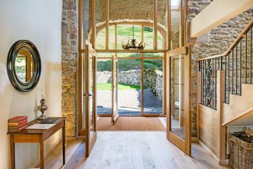 a hallway with a large glass door and a stair case at Williamston Barn in Slaggyford