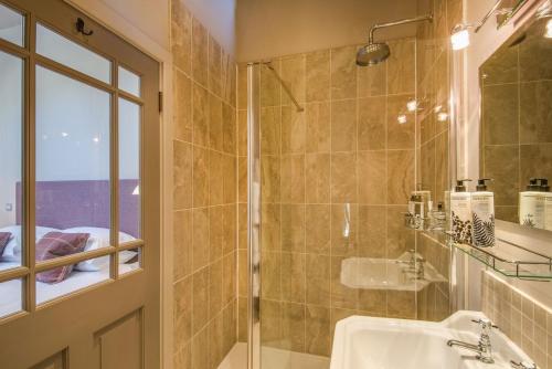 een badkamer met een douche, een wastafel en een spiegel bij Williamston Barn in Slaggyford