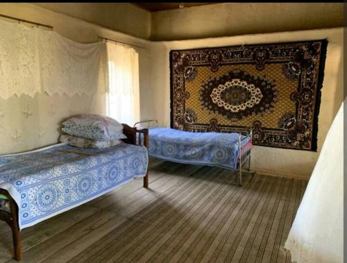 1 dormitorio con 2 camas y tapiz en la pared en Holidayy Housee, en Aşağı Layski