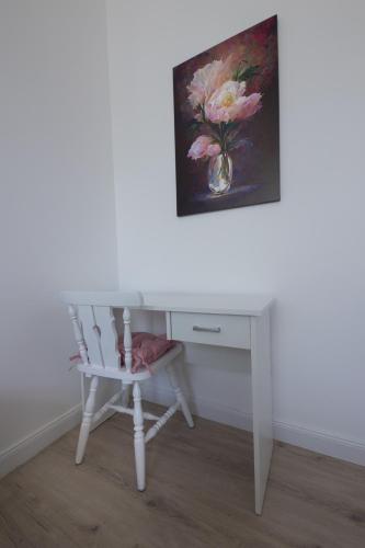 a white desk and a chair with a vase of flowers at Wagner Villa 902 with free private parking in Budapest