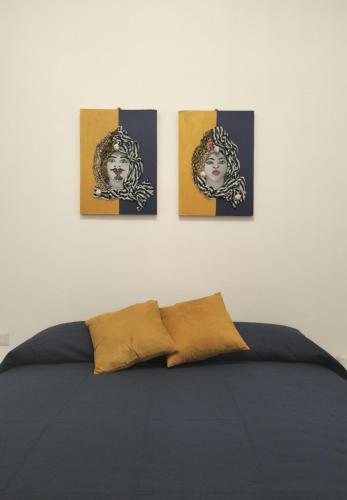 a bedroom with four paintings on a wall with a bed at Casa Basilico' Taormina in Taormina