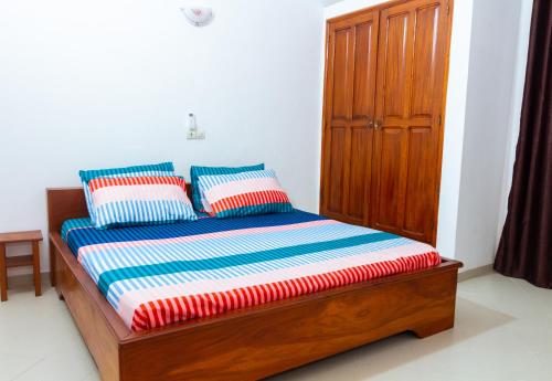 1 cama con 2 almohadas y armario de madera en JRéside Appart XL02 50m2 centre-ville, en Cotonou