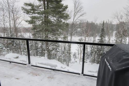 Il dispose d'un balcon enneigé offrant une vue sur la forêt. dans l'établissement Panoramic Lakefront Chalet with Hot Tub & Firepit, à Chertsey