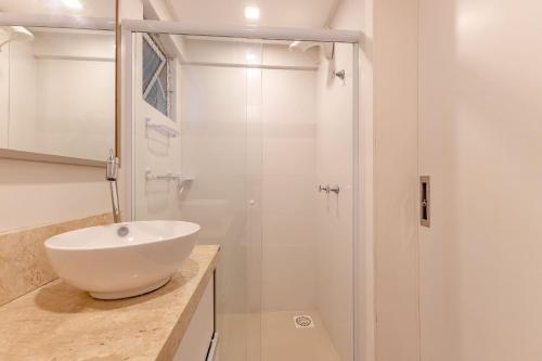 La salle de bains blanche est pourvue d'un lavabo et d'une douche. dans l'établissement Apartamento em Bombas - Ótimo para Famílias, à Bombinhas