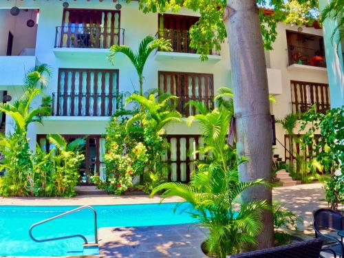 a hotel with a swimming pool in front of a building at Casa Kaz: Penthouse 1 Bedroom in Zihuatanejo