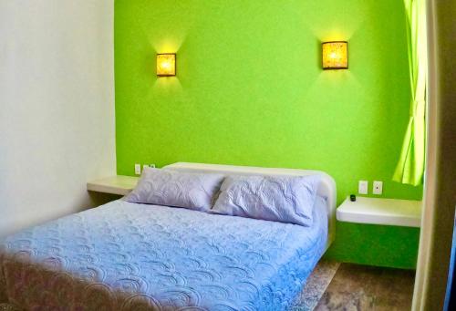 a bedroom with a blue bed and a green wall at Casa Kaz: Penthouse 1 Bedroom in Zihuatanejo