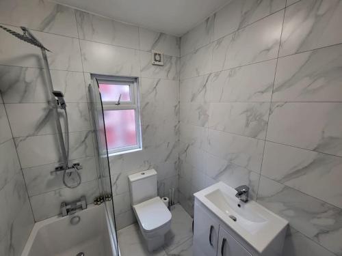 a white bathroom with a sink and a toilet at 4 Bedroom house, 8 min to city! in Manchester