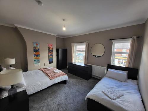 a bedroom with two beds and a mirror at 4 Bedroom house, 8 min to city! in Manchester