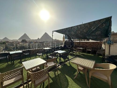 un grupo de mesas y sillas con pirámides en el fondo en Sun light pyramids inn en El Cairo
