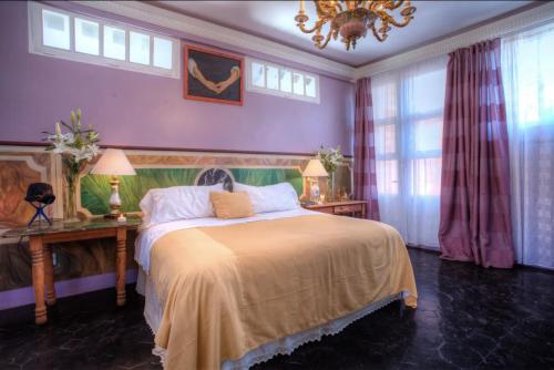 a bedroom with a bed and a chandelier and windows at Hotel Boutique Rivera Del Rio in Puerto Vallarta