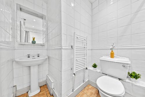 a white bathroom with a toilet and a sink at Kensington Station Proximity 2-Bedroom Apartment, Walk to Station in 2 Minutes in London