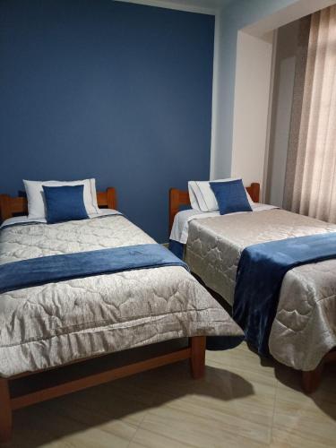 a bedroom with two beds with blue walls at HOSPEDAJE VALLE VERDE in Oxapampa