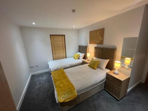 1 dormitorio con 2 camas con sábanas amarillas y 2 lámparas en AO Arena flat Manchester, with parking en Mánchester