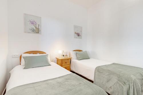 2 camas en una habitación con paredes blancas en Casa Roure-4BR-Piscina-BBQ-Vistas Mar-Ping-Pong, en Sant Cebrià de Vallalta