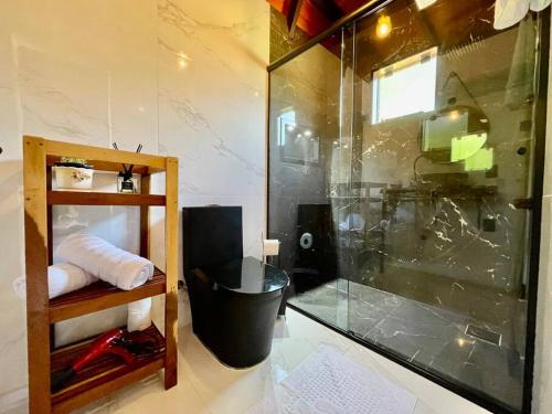 a bathroom with a shower with a glass wall at Chalé no Litoral 01 in Torres