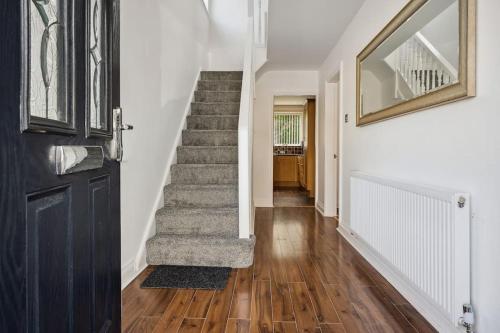 a hallway with a staircase and a door with a rug at house in Heald Green village in Manchester