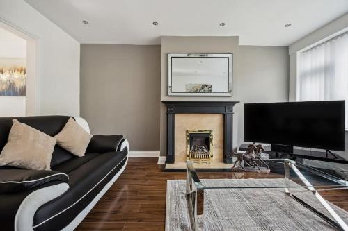 a living room with a black couch and a fireplace at house in Heald Green village in Manchester