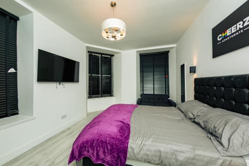 亞伯丁市的住宿－CHEERZ Apartments，一间卧室配有一张大床和一台平面电视