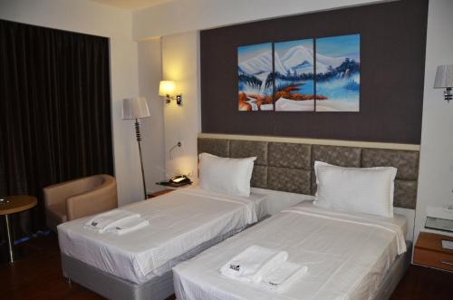 a hotel room with two beds with white sheets at Maha Bodhi Hotel.Resort.Convention Centre in Bodh Gaya