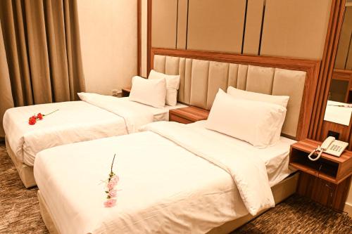 2 camas en una habitación de hotel con sábanas blancas en بيوت ملاذ للشقق الفندقية en Yeda
