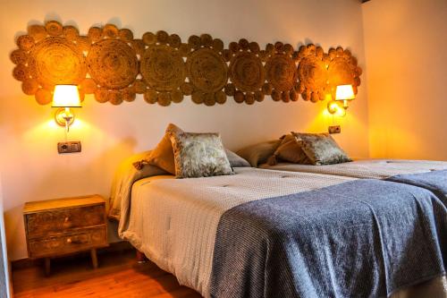 een slaapkamer met 2 bedden en 2 lampen aan de muur bij Fogar de Lecer in Arzúa