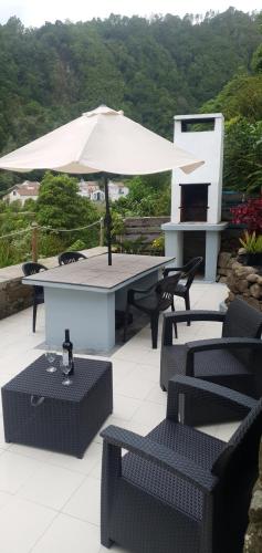 a patio with an umbrella and tables and chairs at Casa do Monte in Faial da Terra