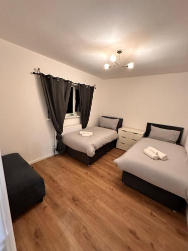 two beds in a room with wooden floors at Kriss house in Bristol