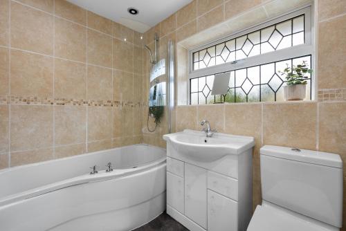 a bathroom with a tub and a sink and a toilet at Monthly Rates Cosy 3 Bed Free Parking -Contractors Families in Solihull