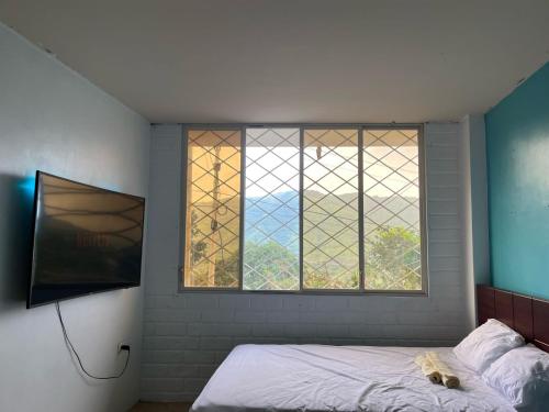 a bedroom with a bed and a large window at La Orquidea Airbnb in Piñas
