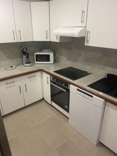 a kitchen with white cabinets and a stove top oven at Villa Aléo in Sainte-Anne