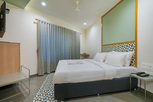 a bedroom with a large white bed and a television at ARYAAS REGENT in Cochin