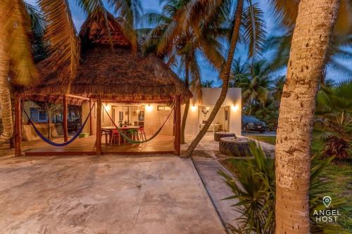 a hut with a hammock in front of a house at A Sublime Beach Getaway Perfect for a Family Gathering in El Cuyo