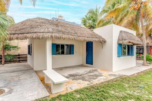 a small white house with a thatched roof at A Sublime Beach Getaway Perfect for a Family Gathering in El Cuyo