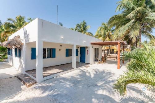 a white house with palm trees in front of it at A Sublime Beach Getaway Perfect for a Family Gathering in El Cuyo