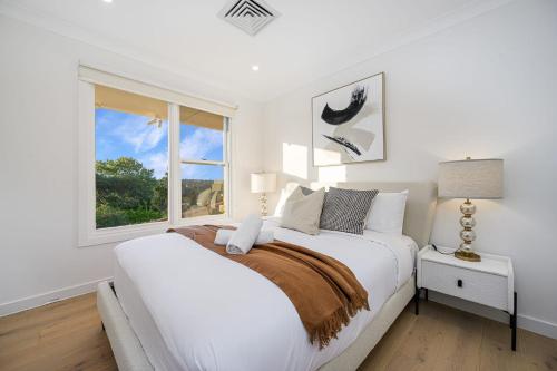 Un dormitorio blanco con una cama grande y una ventana en Large 5BD w Amazing Hill view in East Lindfield, en Forestville