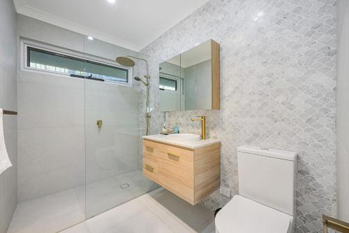 y baño con aseo, lavabo y ducha. en Large 5BD w Amazing Hill view in East Lindfield, en Forestville