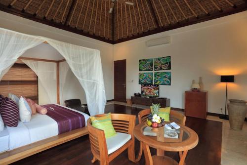 a bedroom with a bed and a table and chairs at Villa The Jiwa in Tanjung