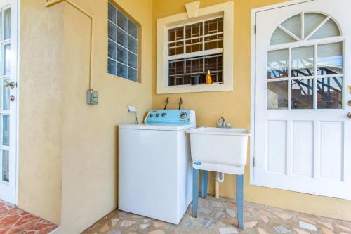 a white refrigerator next to a sink next to a door at Oceanview Terrace I Full Kitchen I Steps to Beach I WiFi in Saint Lucy
