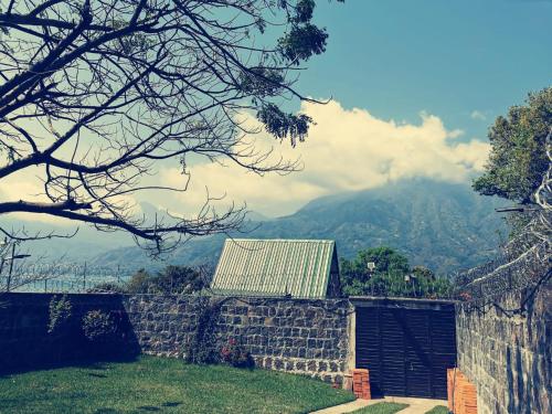 un mur en pierre avec un bâtiment et une montagne dans l'établissement PEDACITO DE CIELO, à Santiago Atitlán