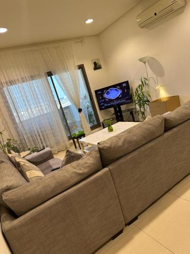 a living room with a large couch and a flat screen tv at Hash&Jazz in Manama