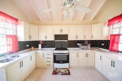 a kitchen with white cabinets and a ceiling fan at Beachy Cottage I Kitchen I Wi-Fi I Shaded Cabana I Parking in Saint Philip