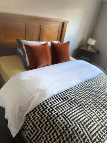 a bed with orange and black pillows on it at Spacious Apartment NEC BHX in Solihull