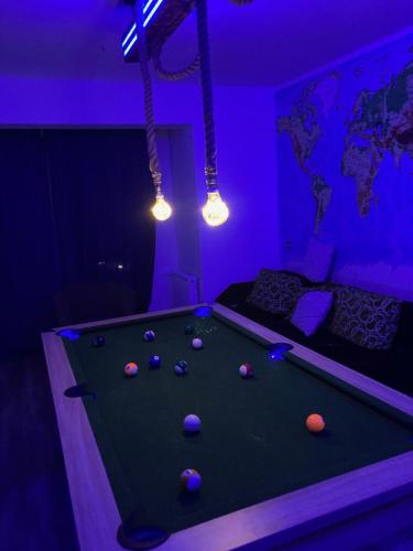una mesa de billar en una habitación con luces moradas en Apartament Jeziorna Olecko, en Olecko