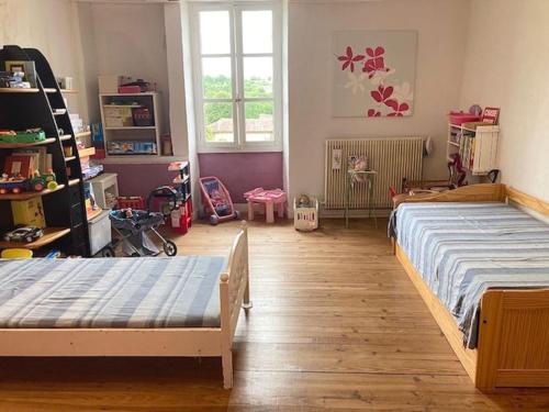 1 dormitorio con 2 camas y juguetes en Maison de campagne 1850 Piscine privée en Aigre